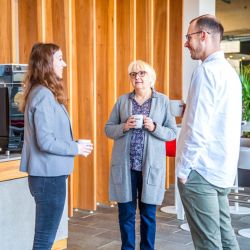 Kolleg:innen treffen sich zum Austausch im Foyer auf einen Kaffee.